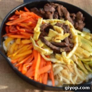 A skillet of korean bibimbap, ready to be mixed and enjoyed.