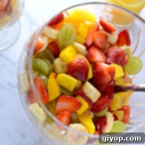 Effortless Fruit Salad Delight 2 A big glass bowl of fresh fruit salad with a serving spoon.