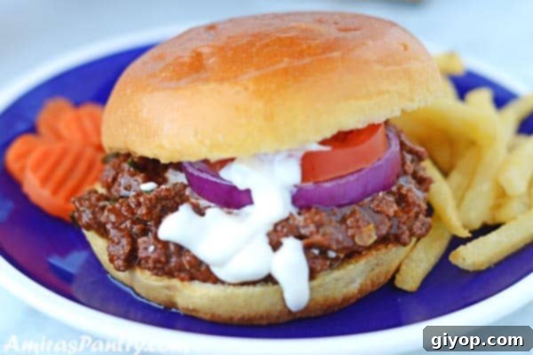 A shawarma spiced sloppy joes sandwich with white shawarma sauce dripping and showing tomato and onion rings in the sandwich.