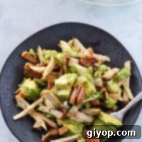 A black plate with avocado chicken salad on it with the whole serving bowl in the back.