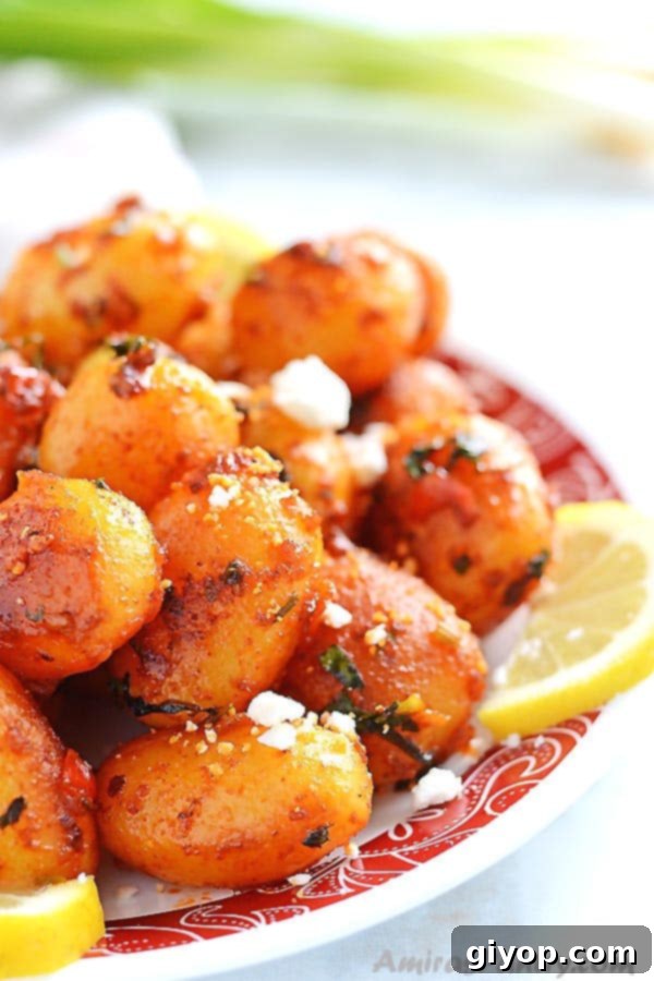Fiery Lebanese Potatoes 3 A white plate filled with spicy potato salad sprinkled with feta cheese and lemon rinds.
