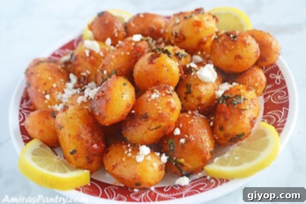 Fiery Lebanese Potatoes 4 A white plate filled with spicy potato salad sprinkled with feta cheese and lemon rinds.