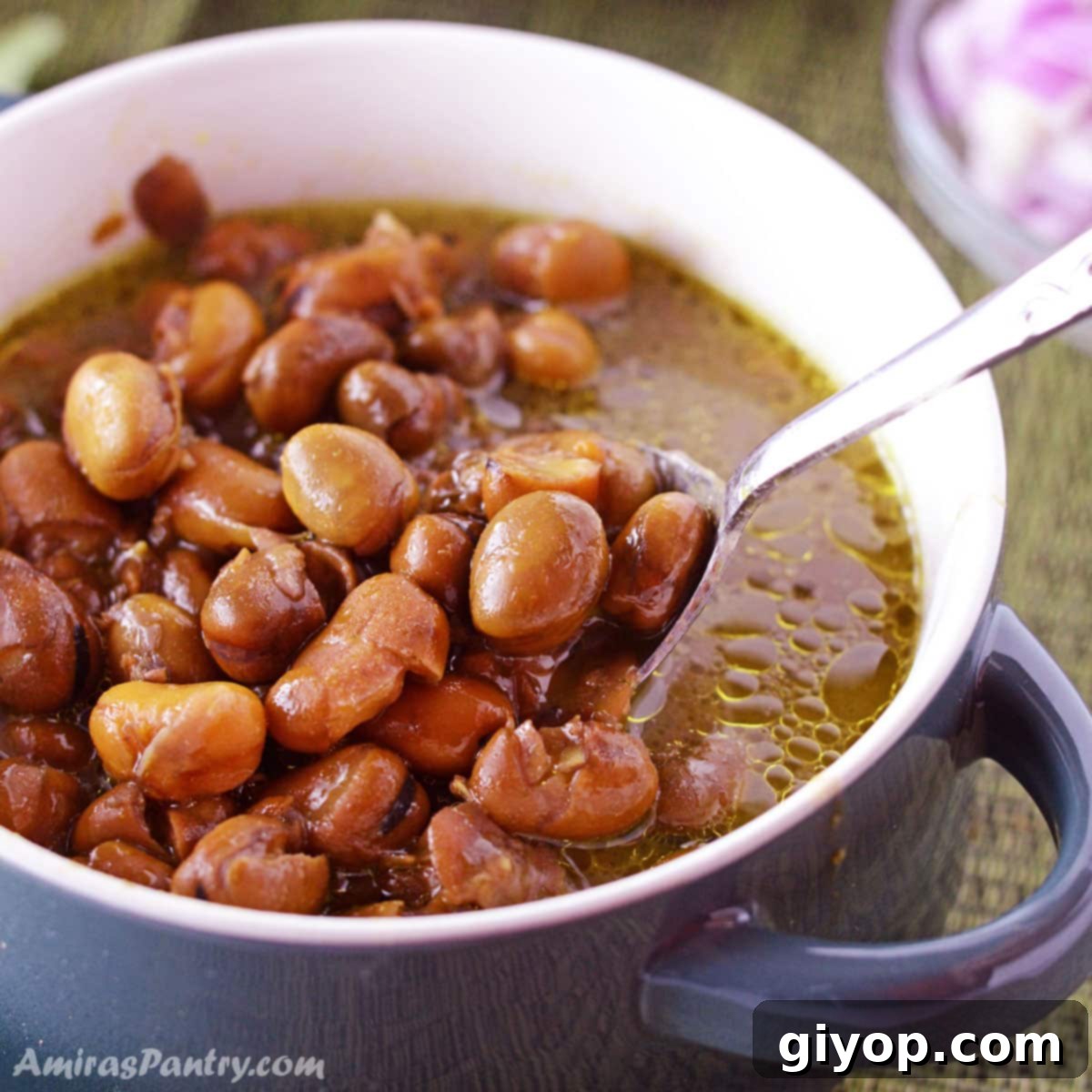 A bowl of Ful Medames with a spoon, showing the creamy texture of the cooked beans.