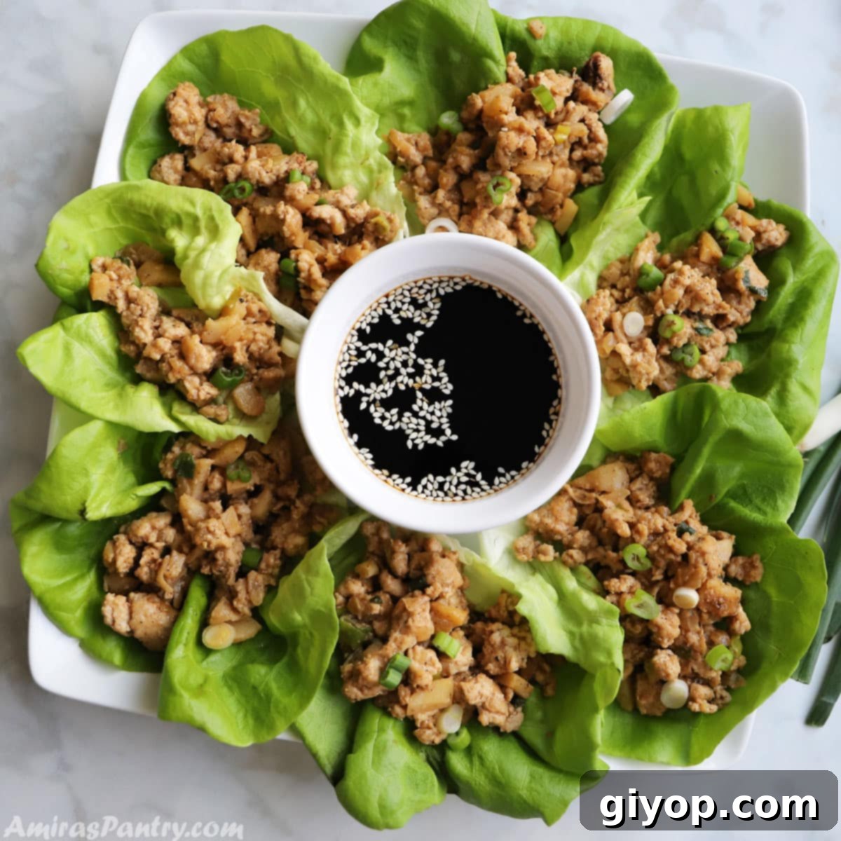 A serving platter filled with chicken lettuce wraps and a sauce bowl in the middle, ready to be enjoyed.