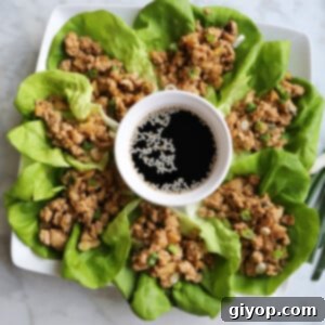 A serving platter filled with chicken lettuce wraps and a sauce bowl in the middle.