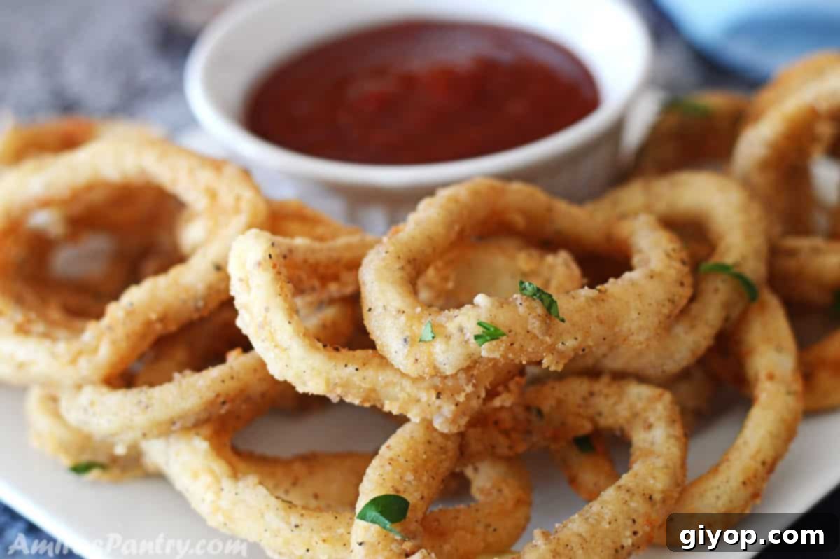 A serving of crispy fried calamari garnished with fresh parsley, with a bowl of dipping sauce in the background.