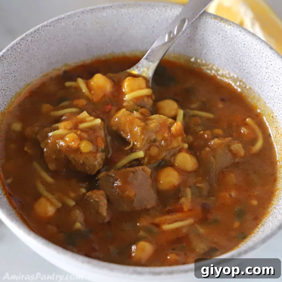 Hearty Moroccan Harira Lentil and Chickpea Soup 2 A bowl of Harira soup with a spoon resting in it and a lemon wedge on the side, ready to be served.
