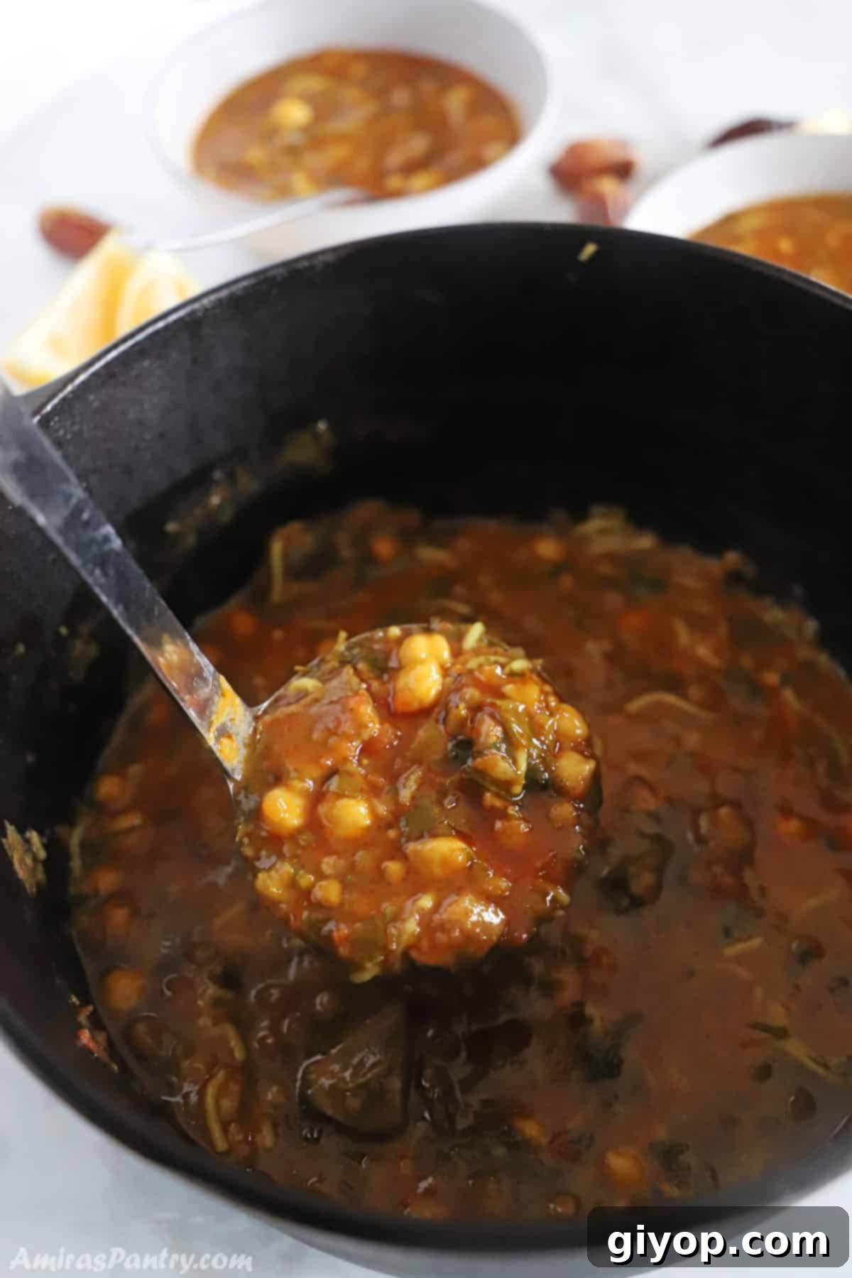 Hearty Moroccan Harira Lentil and Chickpea Soup 6 A ladle scooping rich Harira soup out of a rustic cast iron pot, showcasing its hearty texture.