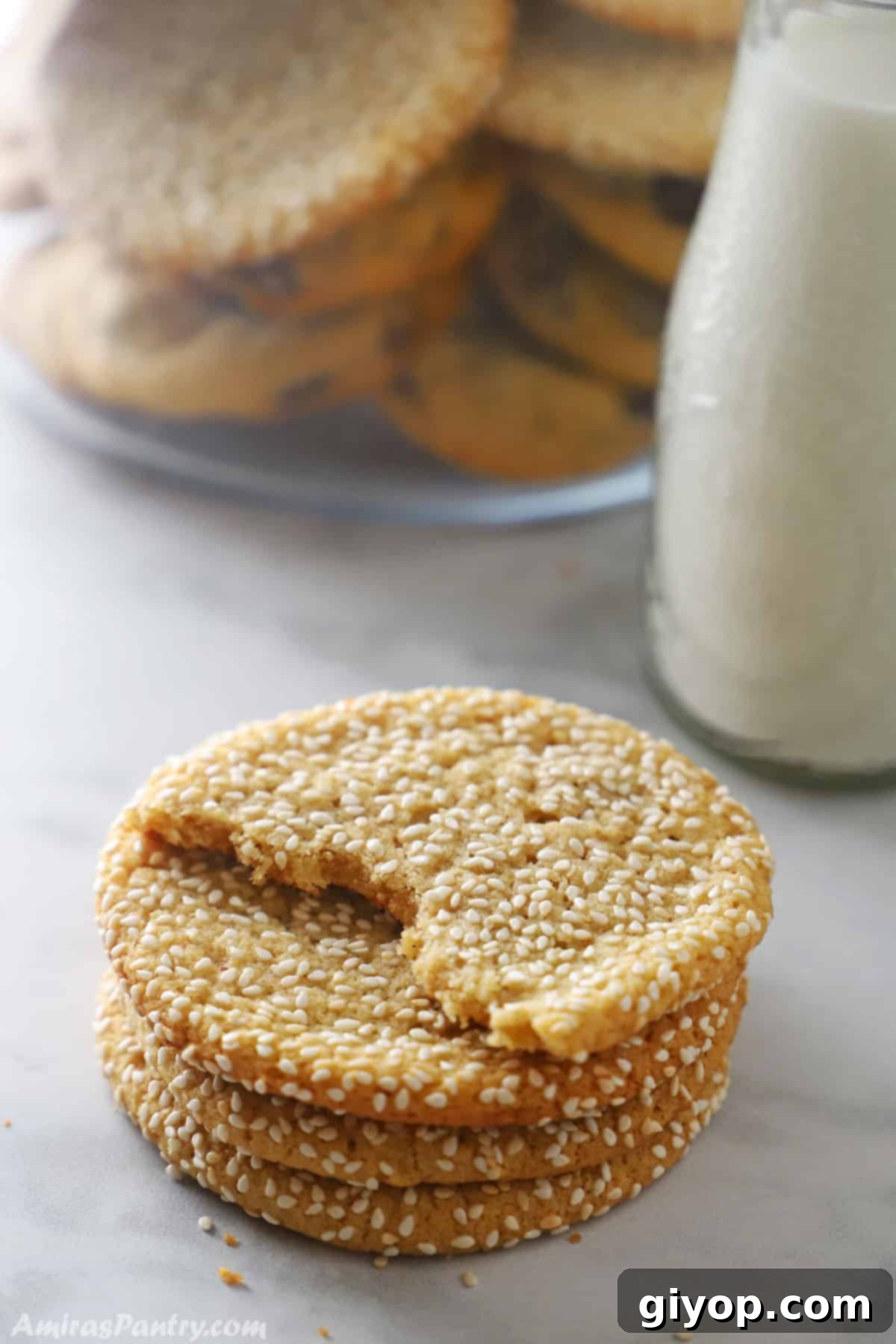 A stack of golden tahini cookies beside a glass bottle of milk, highlighting their homely appeal.