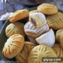 cookies on a black metal serving plate with one maamoul on the top and cut in half to show date filling.