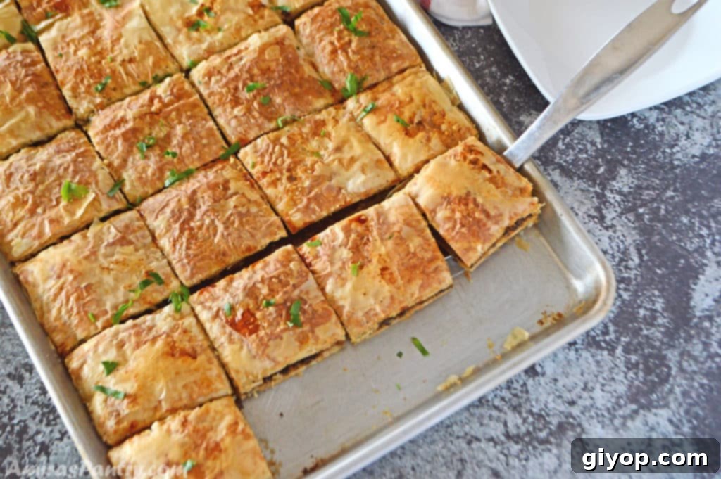 A baking sheet with phyllo squares cut side by side and placed on a dark grey table.