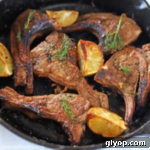 lamb chops on a cast iron skillet decorated with fresh dill and lemon wedges.