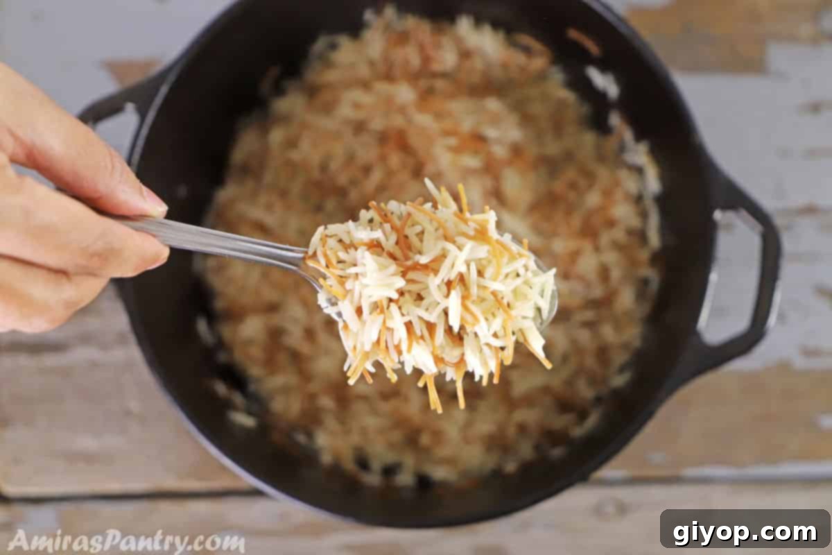 A hand holding a serving spoon of Lebanese rice over a pot of rice placed on a wooden table, ready to be served.