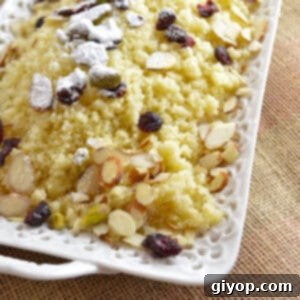 Sweet couscous in a white serving plate garnished with nuts and raisins.