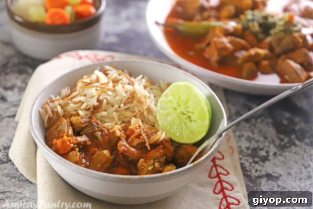 A bowl of okra stew with Lebanese rice and a lime on the side.