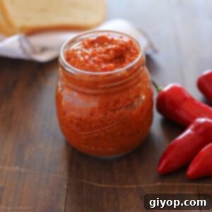 Crafting Authentic Harissa at Home 7 A jar of Harissa on a wooden surface with some chili peppers on the side and bread on the back.