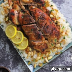 A whole duck placed on a serving platter over a bed or rice garnished with roasted nuts.