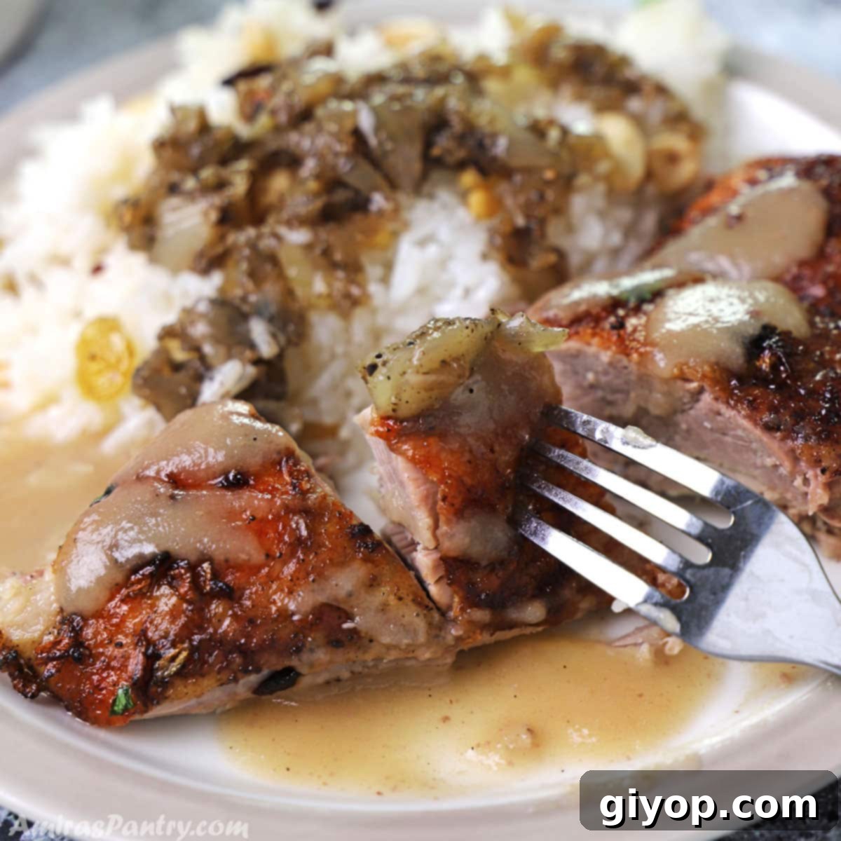 A fork holding a succulent piece of roast duck breast, served on a plate with aromatic rice and savory onion stuffing, showcasing the delicious meal.
