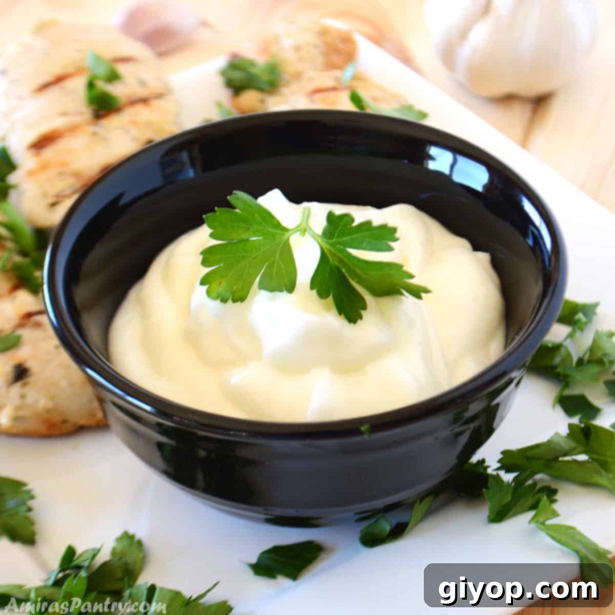 Authentic Lebanese Toum Garlic Sauce Recipe 2 Garlic dip in a small black bowl garnished with parsley