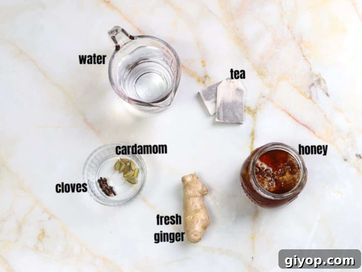 Cardamom tea ingredients on a marble surface, including whole cardamom pods, sliced ginger, and cloves.