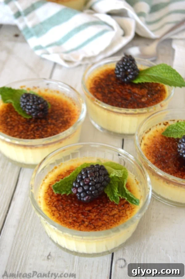 A close up of individual creme brulee in cups with fresh berries, ready to be enjoyed.