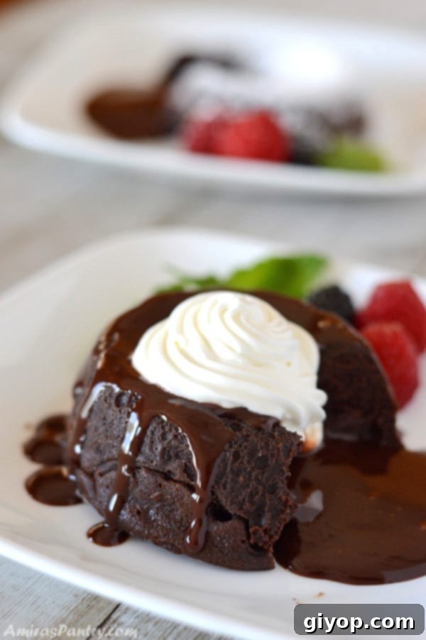 A close up of a piece of chocolate molten cake on a plate, with cream on the side, highlighting its rich texture.