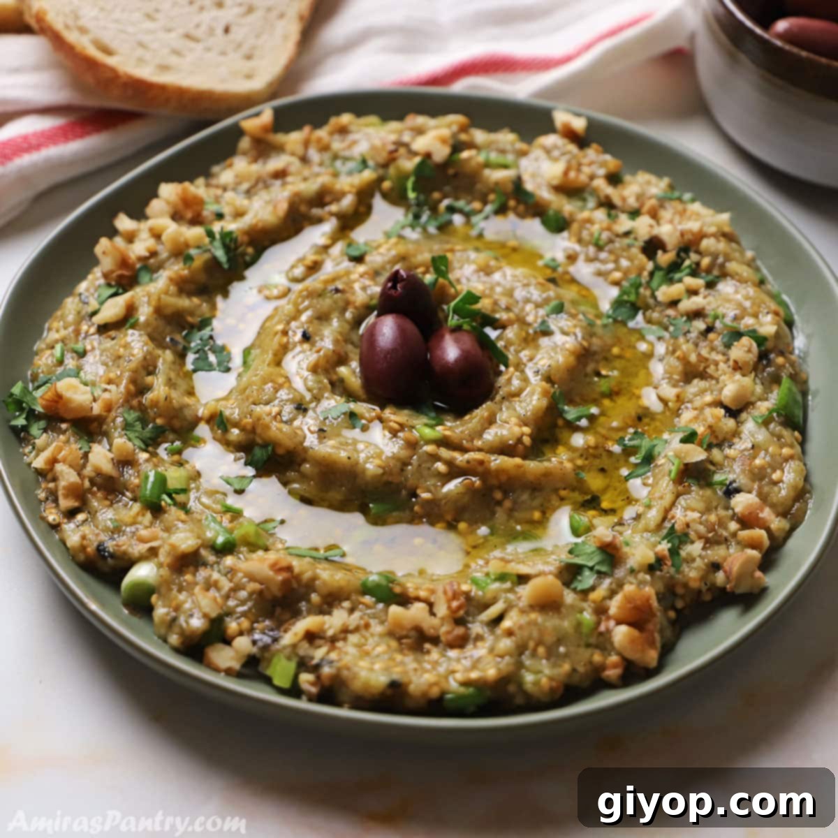 Greek eggplant dip placed in a green plate and garnished with parsley and olive oil.