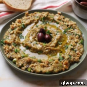 Melitzanosalata served on a green platter garnished with parsley chopped walnuts and kalamata olives.