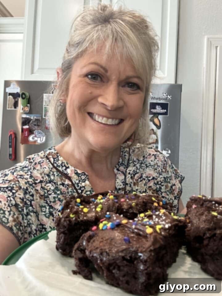 Melinda in the kitchen holding a plate of chocolate cake slices.