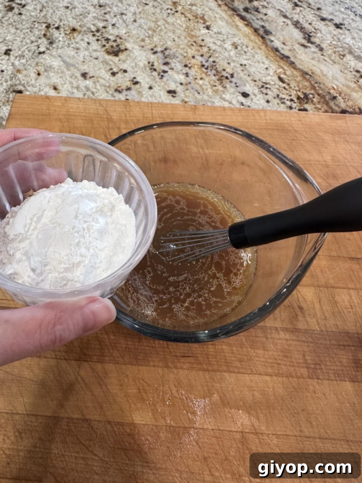 Cornstarch added to sauce in a measuring cup.