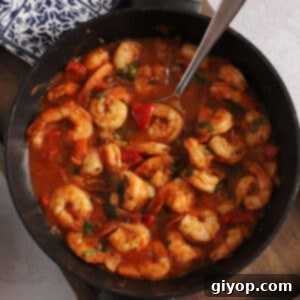 An overhead image of a savory shrimp stew in a pot, garnished with fresh herbs.