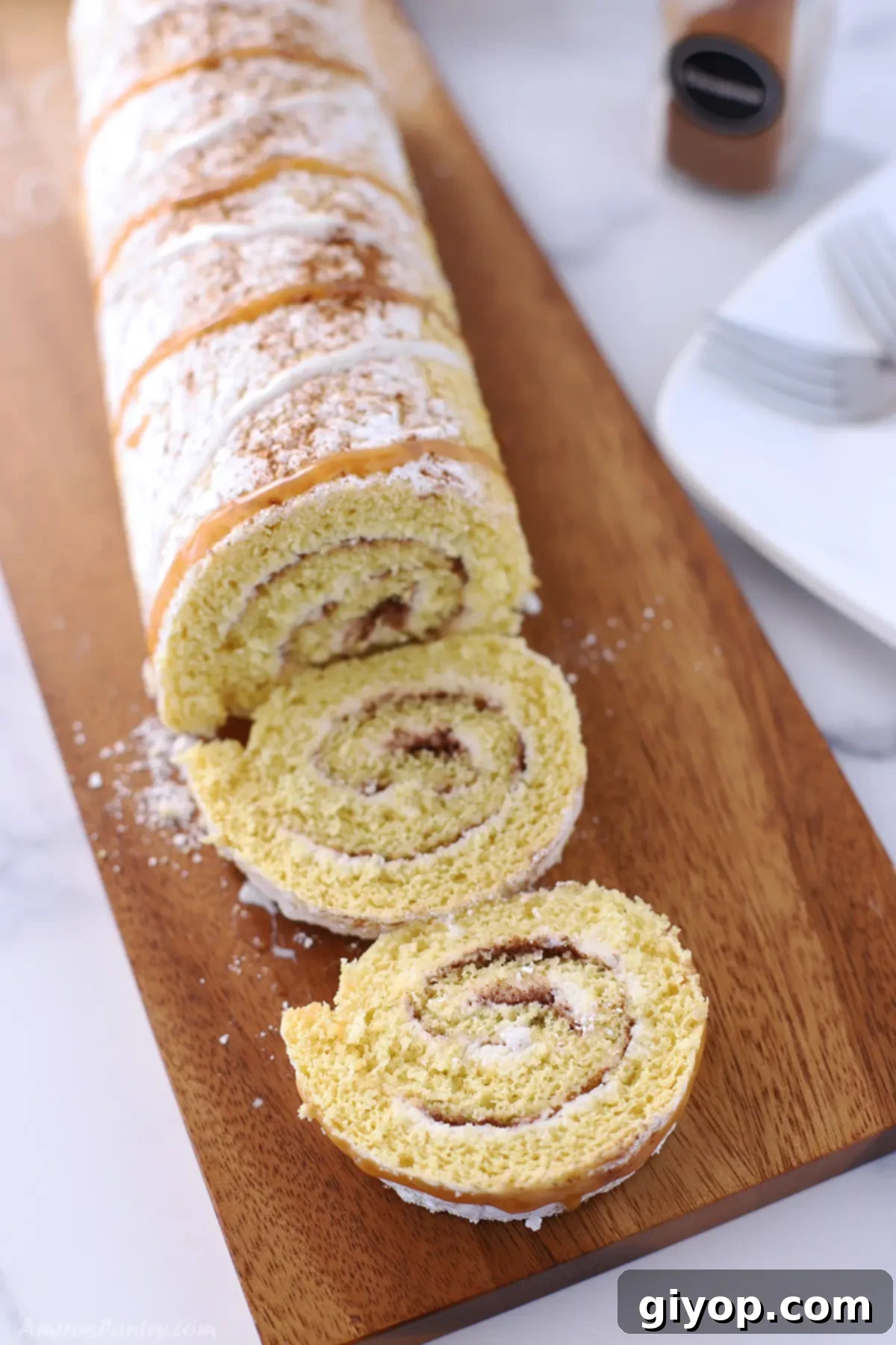 Ultimate Cinnamon Cake Roll Recipe 2 Super moist cinnamon cake roll on a wooden cutting board, ready to be served.