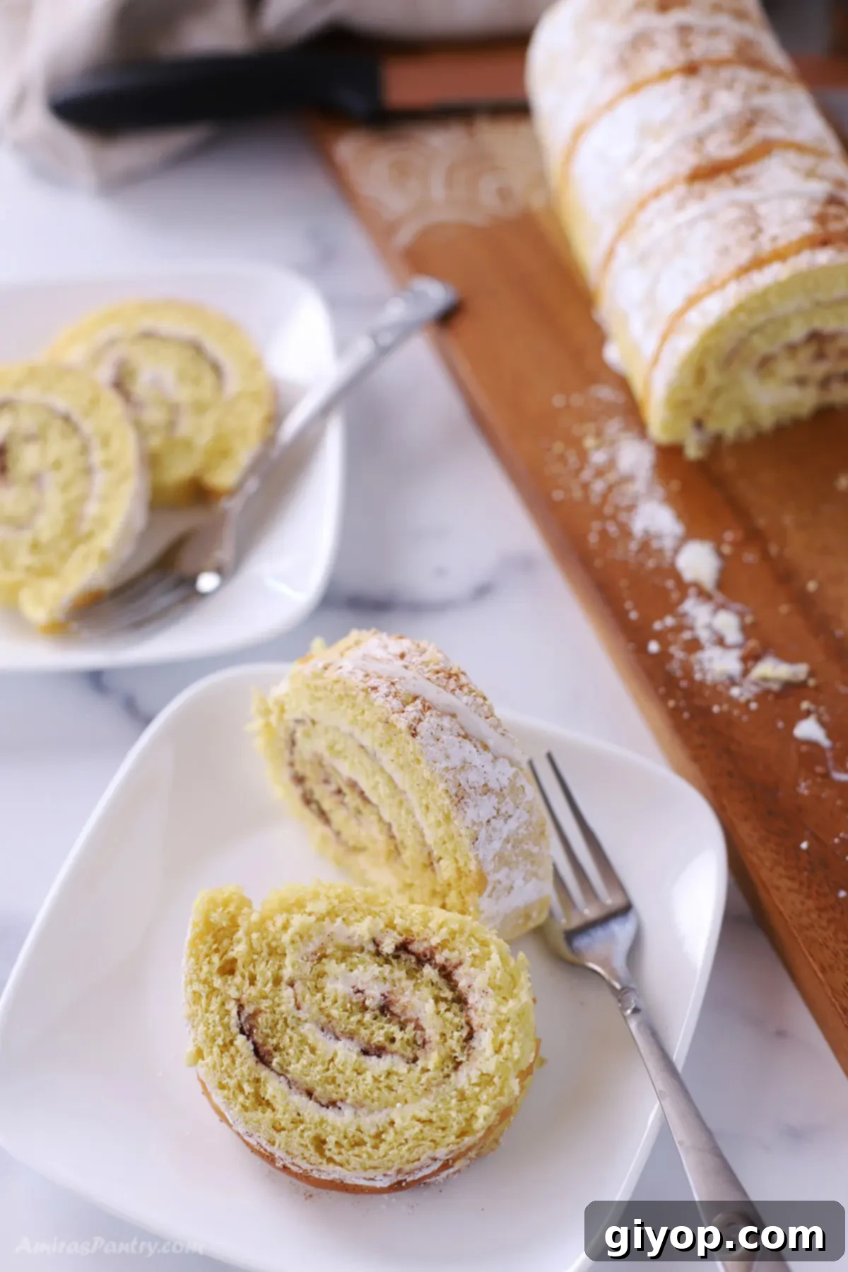 Ultimate Cinnamon Cake Roll Recipe 5 A perfectly sliced cinnamon Swiss roll presented on a white plate, showcasing its beautiful spiral layers and creamy filling.