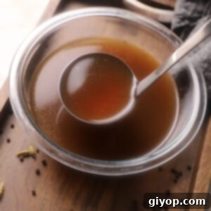 A ladle scooping some bone broth from a big bowl.