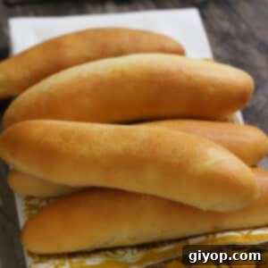 A stack of hot dog buns placed on a kitchen towel, showcasing their golden-brown crust.