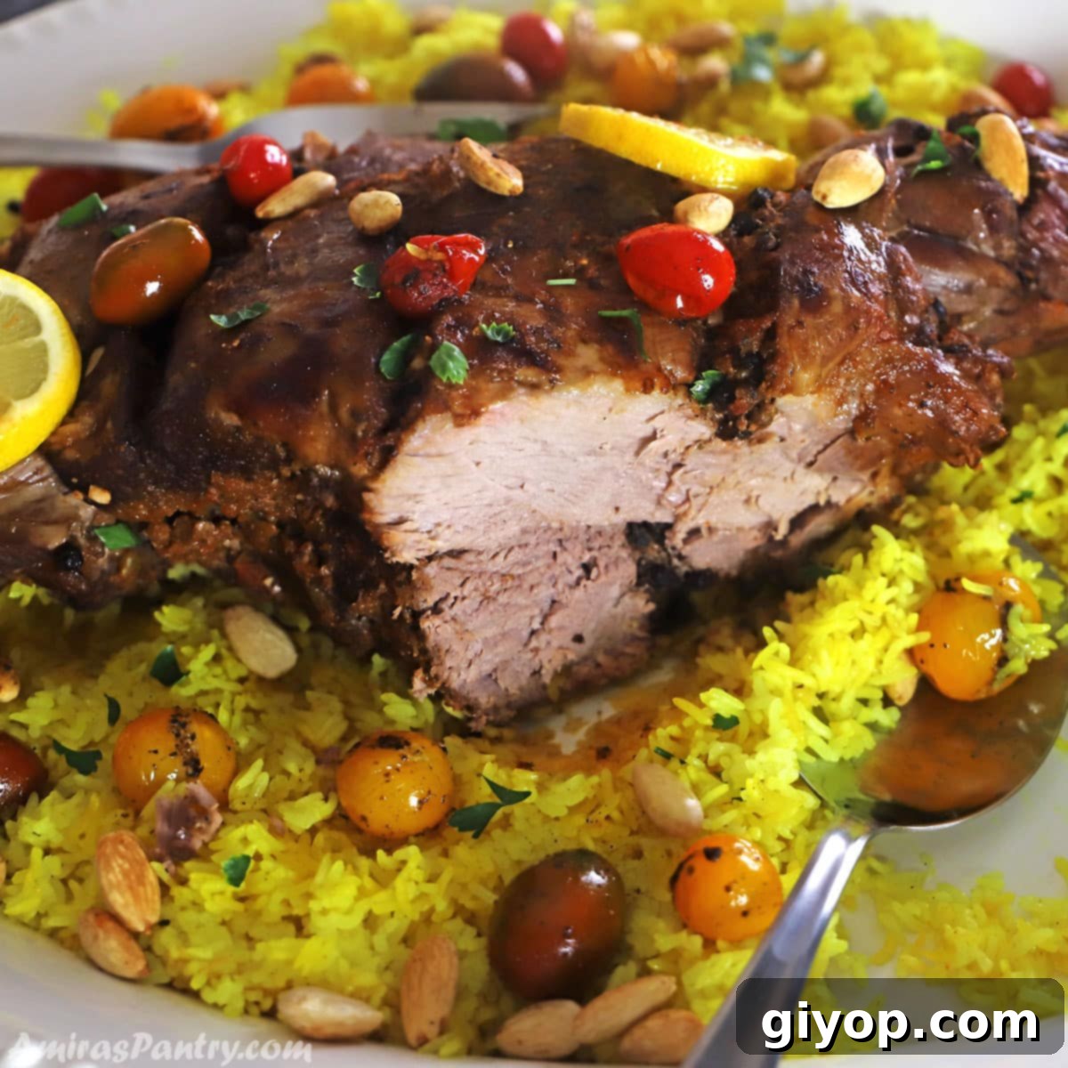 Spiced Middle Eastern Lamb Leg 2 A close look at a leg of lamb with a piece carved out on a yellow rice platter, garnished with herbs.