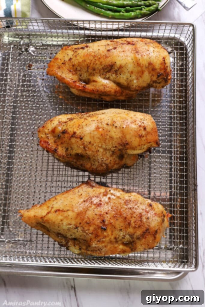 Perfectly golden brown stuffed chicken breast resting on an air fryer basket, showing its crispy exterior and succulent filling.