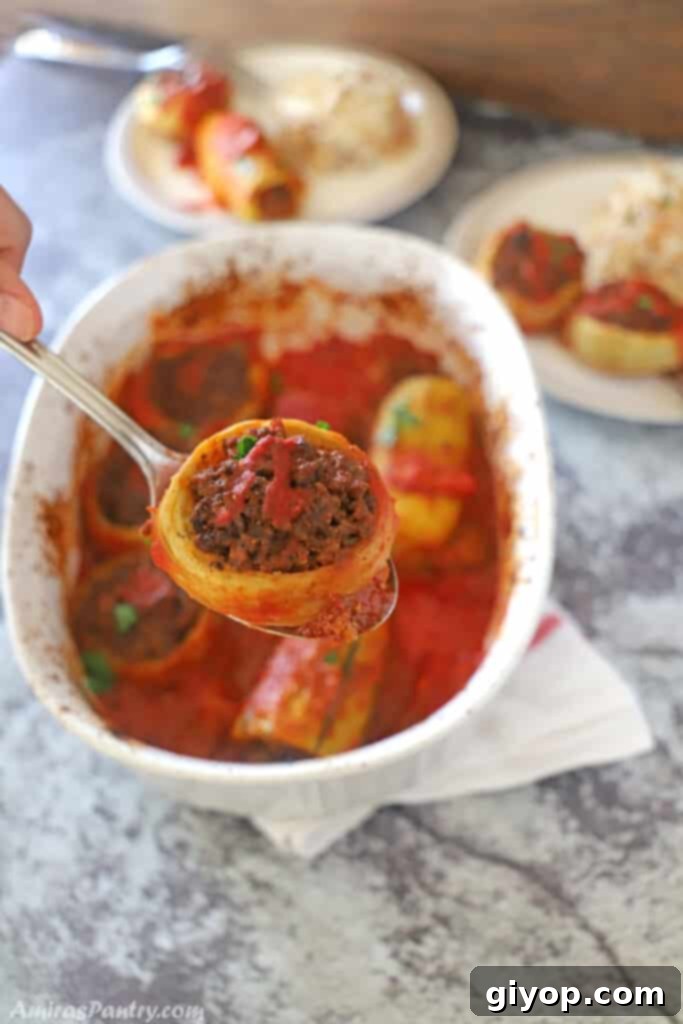 A close-up of a hand holding a spoon, scooping into a tender artichoke heart generously stuffed with seasoned ground meat.