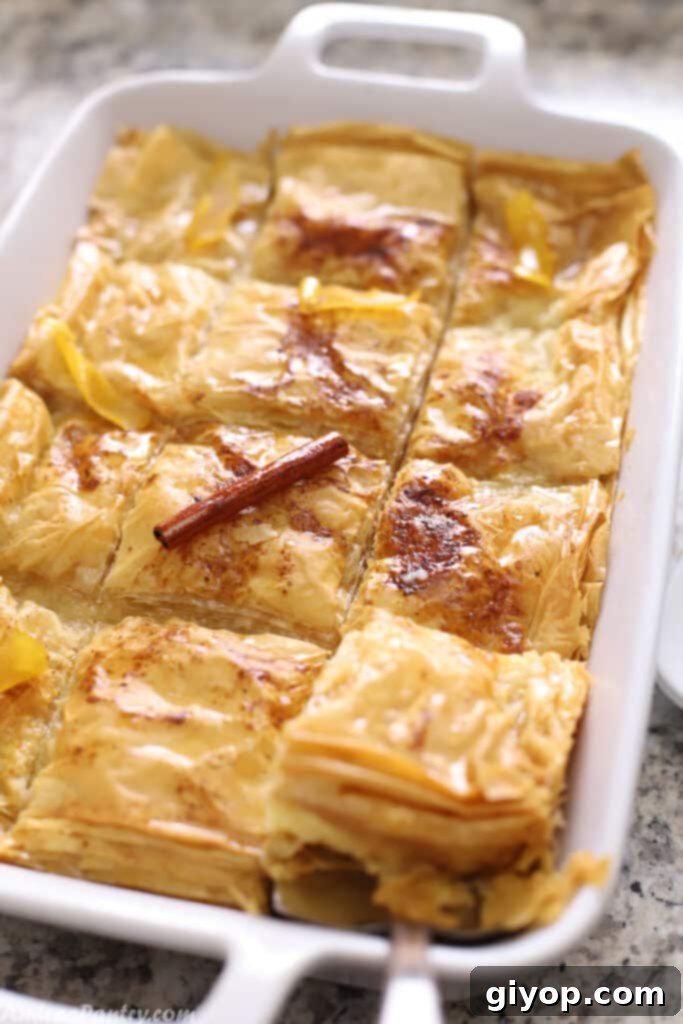 A golden brown Galaktoboureko dessert in a white oven dish, showcasing its crispy filo layers and creamy filling.