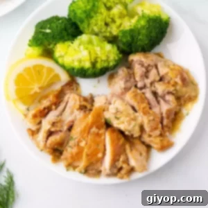 Zesty Lemon Dill Chicken 2 Lemon dill chicken on a white plate with broccoli and a slice of lemon.