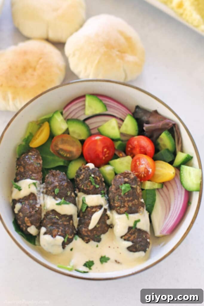 Meal Plan 6 A vibrant plate featuring Lebanese Kafta kabobs, drizzled with creamy tahini sauce, accompanied by a fresh green salad, viewed from above.