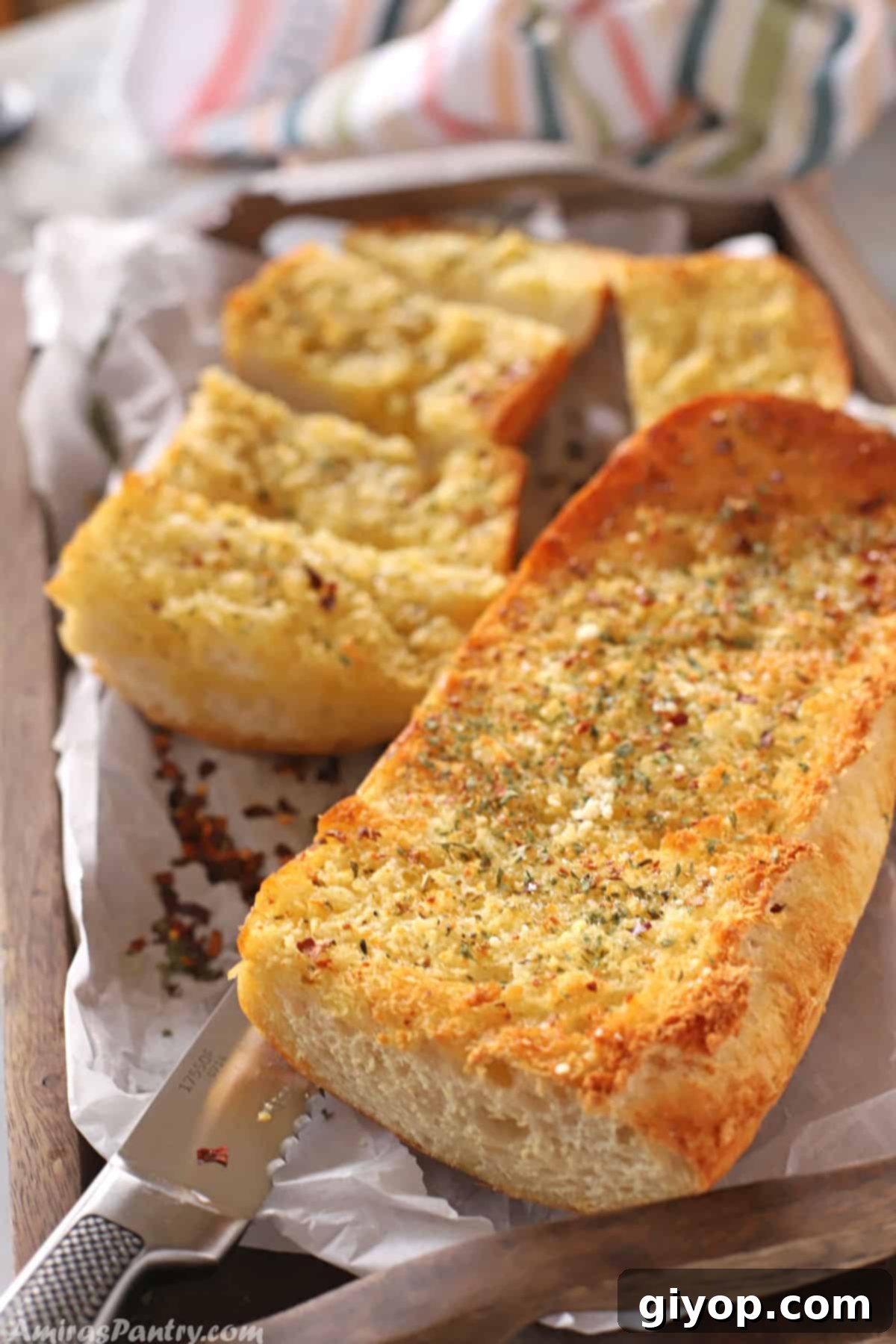 Crusty garlic bread on a tray with a knife.