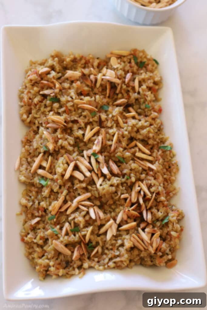 Meal Plan 8 2 A hearty and appealing serving of Freekeh Pilaf, generously topped with an assortment of golden-brown toasted nuts, presented on a pristine white serving platter.