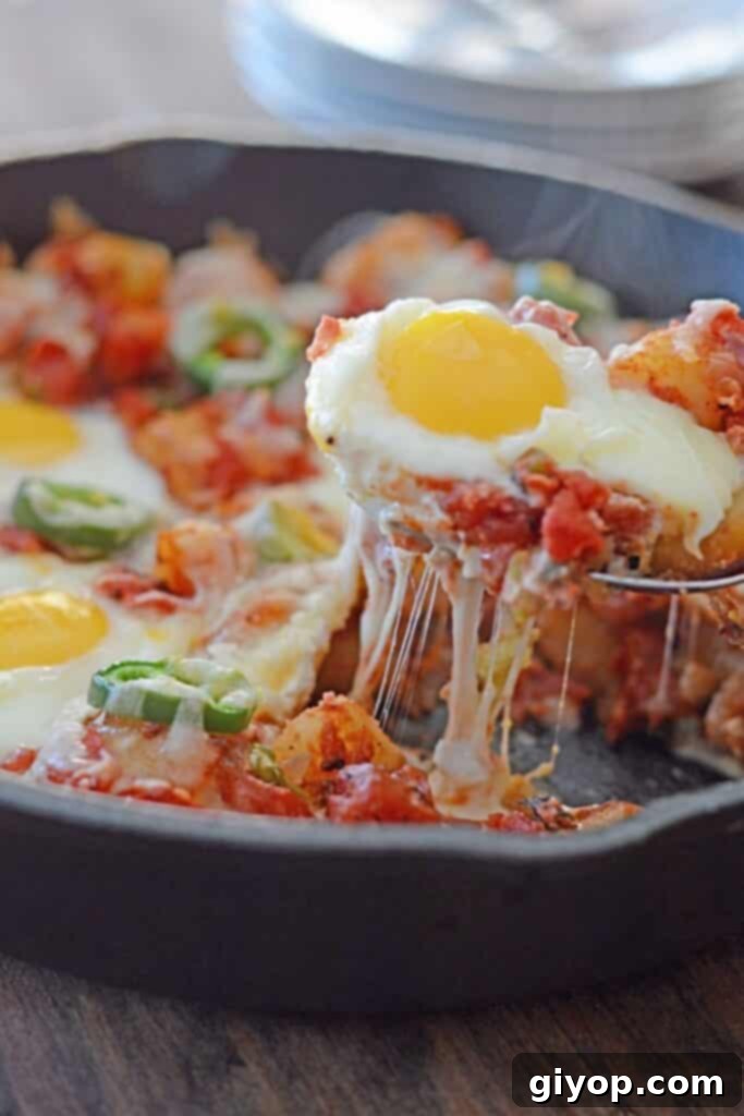 A spoon scooping some potato shakshuka from a skillet, showcasing the rich tomato sauce and perfectly cooked eggs.