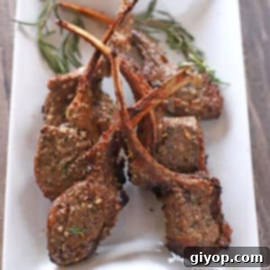 An overhead view of a white serving plate with lamb chops in it.