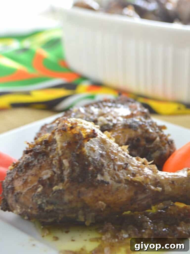 Perfectly baked chicken drumsticks, golden brown and glistening with olive oil, served on a pristine white plate.