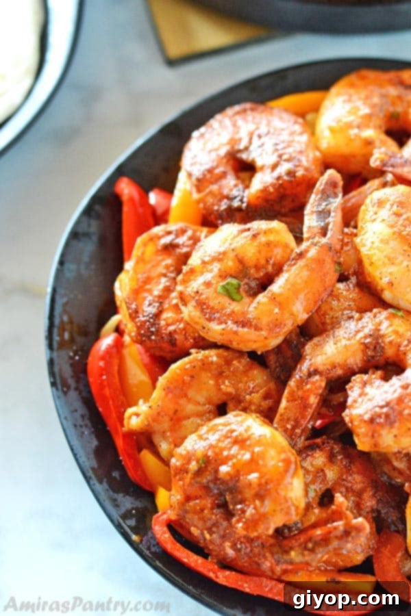 Sizzling shrimp fajitas served on a black plate with vibrant sautéed onions and colorful bell peppers, ready to be wrapped.