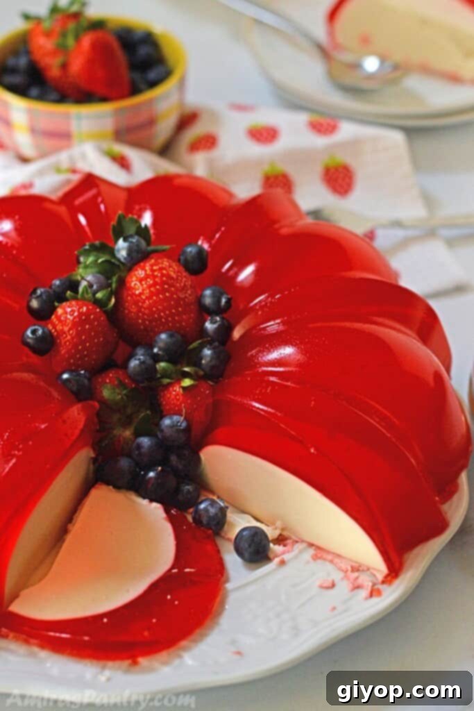 Elevated Eating Guide 7 A vibrant strawberry Jello mold, beautifully sliced from the middle, with a piece cut out to showcase its delicate cream cheese layer within.