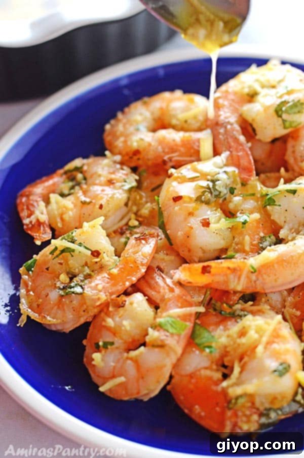 Succulent shrimp scampi served on a blue plate with a spoon delicately pouring more garlic butter sauce over the top.