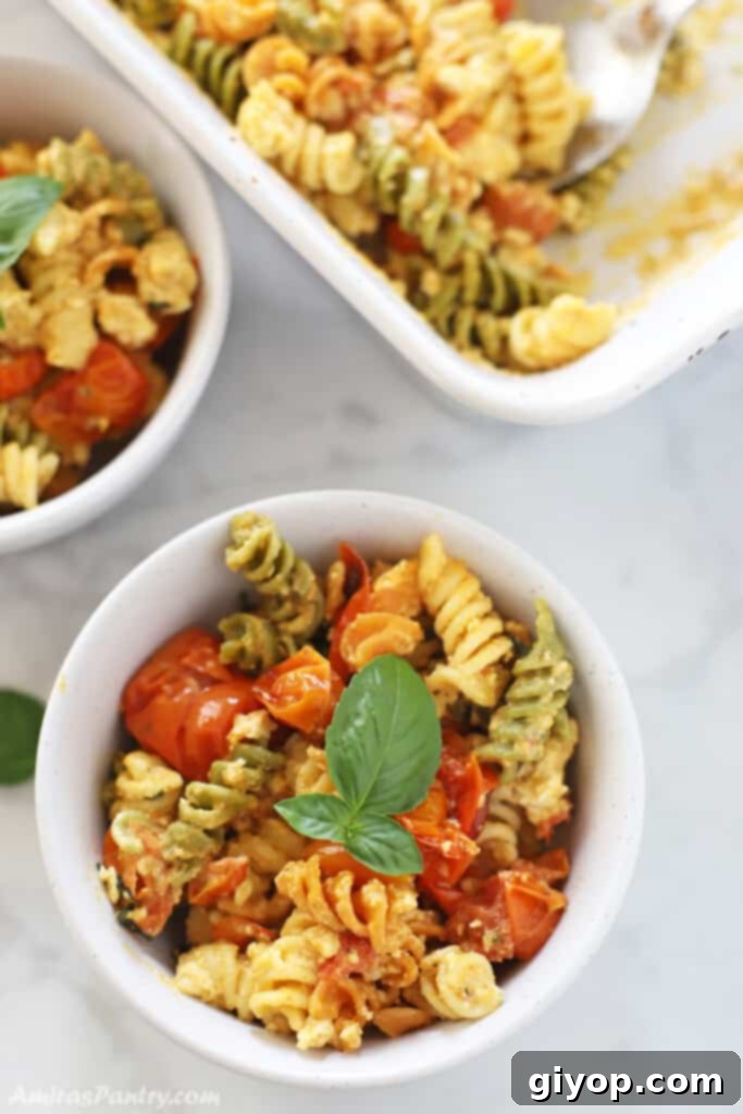 baked feta pasta in a white bowl garnished with fresh basil.